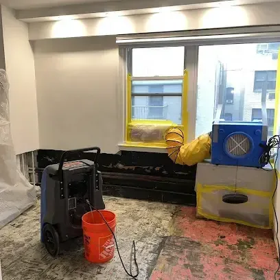 A dehumidifier and an air mover running in a room where the wet flooring was pulled up to dry the floor