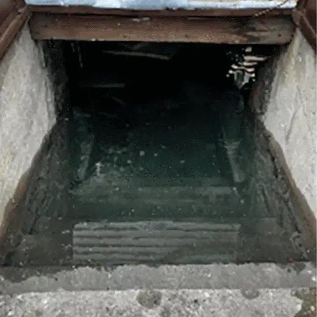 Floodwater pooled deep in a below-grade opening after a heavy storm